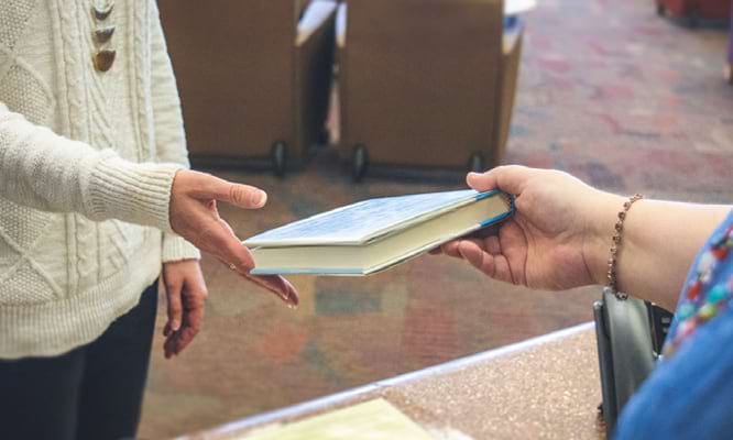 Someone handing a book to someone else